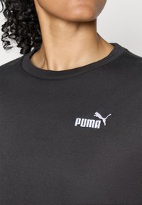 T-shirt in cotone nero con collo tondo e logo "PUMA" ricamato in bianco, con il design di un puma in salto sul petto.
