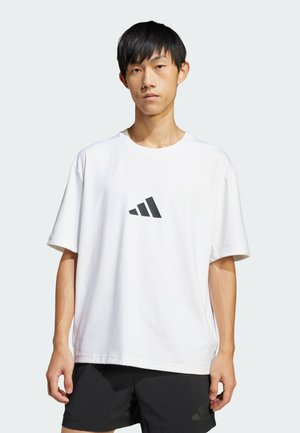 Weißes Baumwoll-T-Shirt mit kurzen Ärmeln, mit einem schwarzen Adidas-Logo in der Mitte. Einfaches, lockeres Design mit Rundhalsausschnitt.