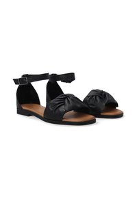 Zwarte leren sandalen met een geknoopt ontwerp bij de teen, enkelband met gesp en een platte zool met een tankleurige binnenzool.