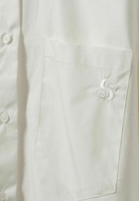 White button-up shirt with a left chest pocket, featuring a subtle embroidered logo in matching white thread. Smooth, lightweight fabric.