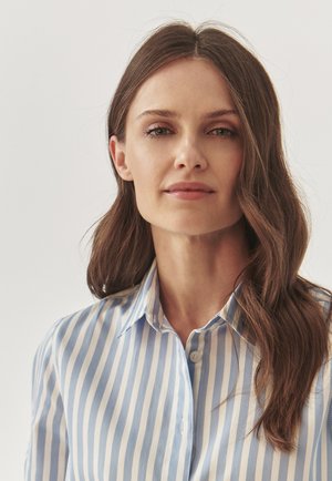 Button-up shirt featuring vertical blue and white stripes, a classic collar, and soft fabric texture. Notable details include a button placket.