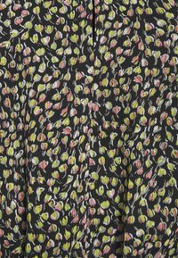 Tissu noir avec de petites formes florales abstraites vertes, roses et blanches dispersées, créant un motif dense et coloré.