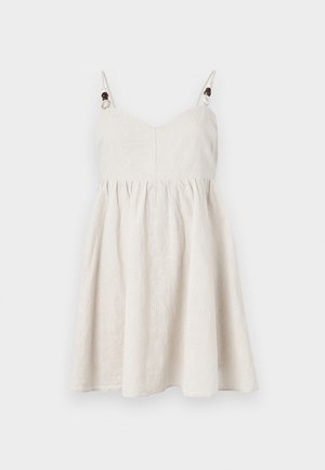 Lniana sukienka w jasnym beżu, z dopasowanym korpusem, rozkloszowanym dołem, regulowanymi ramiączkami ozdobionymi drewnianymi koralikami i marszczeniami.