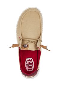 Scarpa da barca in tela beige con superficie testurizzata, lacci elastici, foderatura interna rossa e suola bianca con dettagli di branding discreti.