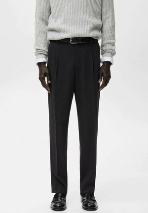 Czarne, dopasowane spodnie o prostych nogawkach i przednich plisach, zestawione z jasnoszarym, prążkowanym swetrem oraz czarnymi skórzanymi butami.