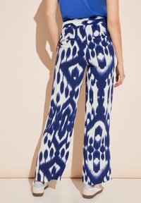 Spodnie o szerokich nogawkach w niebiesko-białym wzorze ikat, z wysokim stanem i lekkiej tkaninie. Gładka faktura i zwiewny fason.
