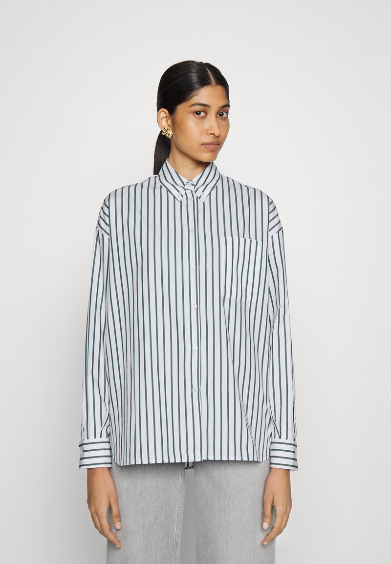 Camicia a righe in blu chiaro e verde, con colletto, taschino frontale e maniche lunghe con dettagli ai polsini. Tessuto dalla consistenza liscia.