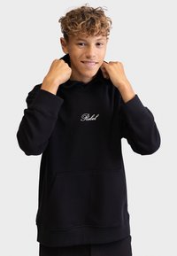 Juodas gobtuvas, pagamintas iš minkštos medžiagos, su išsiuvinėtu baltu "Rebel" logotipu. Jame yra priekinė kišenė ir gumuoti rankogaliai. Paprastas dizainas.