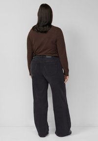 Czarne jeansy o szerokich nogawkach z wysokim stanem, o gładkiej fakturze i dwoma tylnymi kieszeniami, połączone z dopasowanym brązowym topem z długim rękawem.