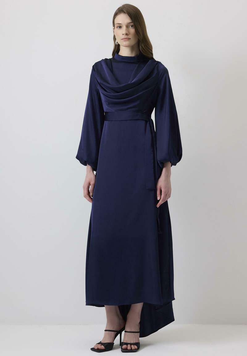 Rochie lungă de culoare albastru închis, cu un front drapat și mâneci tip clopot; are o talie ajustată și o fustă cu margine asimetrică; țesătură fină și ușoară.