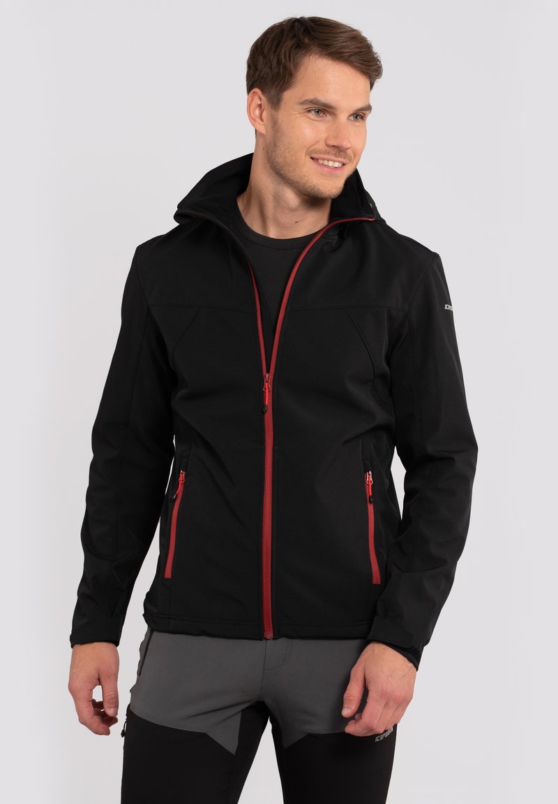 Czarna kurtka softshell z czerwonymi zamkami, wysokim kołnierzem i dwiema przednimi kieszeniami. Projekt jest smukły i dopasowany do wydajności.
