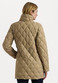 Casaco puffer acolchoado bege com gola alta, apresentando costura em diamante, mangas longas e um corte relaxado. Textura suave e macia.