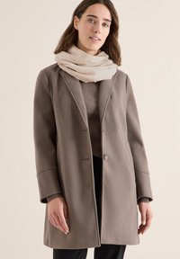 Manteau en mélange de laine brun avec une coupe décontractée, col à revers et deux boutons à l'avant. Assorti à une écharpe beige clair ornée de motifs subtils.