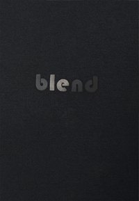 T-shirt nera con una texture morbida, caratterizzata dal logo "blend" in lettere nere e argentate a contrasto sul petto.