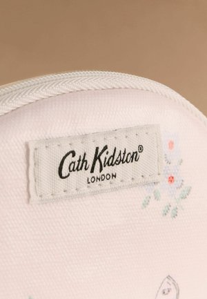 Prim-plan al unui material alb cu textură țesută vizibilă, având o etichetă cusută Cath Kidston London și un model floral mic în culori delicate.