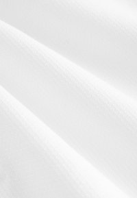 Tela blanca texturizada que muestra un patrón de diamantes, con suaves pliegues y arrugas que crean profundidad y dimensión.