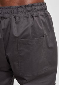 Pantalones oscuros de color gris con cinturilla elástica, que cuentan con un bolsillo lateral. La tela tiene una textura suave y ligera.