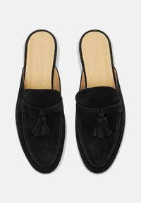 Crne kadirane slip-on cipele s ukrasom od resica, bijelim potplatom, zaobljenim vrhom i šivenim detaljima duž ruba.