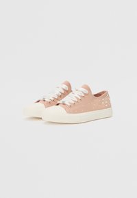 Sneakers in tela rosa con lacci bianchi, dotati di decorazioni sui lati e suola in gomma bianca. Punta rotonda con finitura testurizzata.