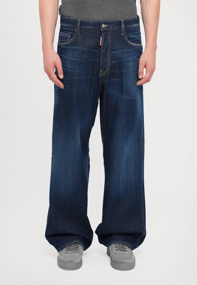 Jean en denim bleu foncé, coupe ample avec jambes droites. Comprend cinq poches, un léger effet délavé et des garnitures en argent au niveau de la taille.