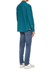 Teal lang mouw shirt met een knoopsluiting kraag, achterplaat en manchetten, gecombineerd met lichtblauwe jeans en witte sneakers.