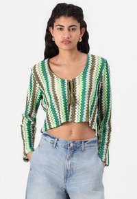 Horgolt stílusú cropped top zöld, barna és fehér cikk-cakk mintákkal. Kerek nyakkivágással és elöl megkötő zárral rendelkezik.