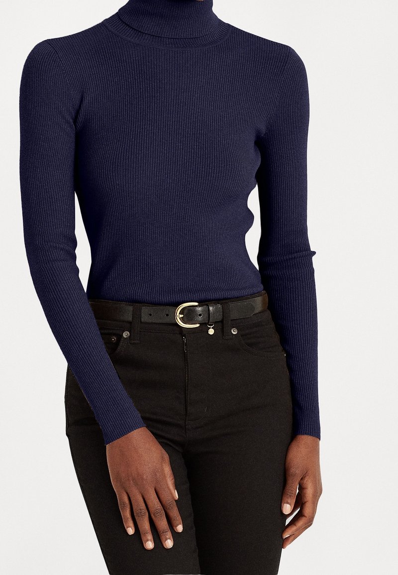 Marinblå ribbad polotröja med långa ärmar, kombinerad med högmidjade svarta jeans och ett smalt svart bälte med ett guldspänne.