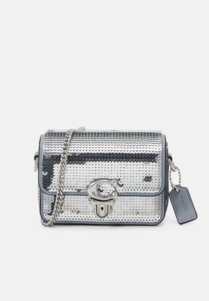 Borsa a tracolla in paillettes argento con forma rettangolare, manico a catena, chiusura metallica e etichetta con logo, caratterizzata da una texture liscia e una superficie riflettente.