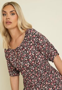 Svart blommig klänning med rosa, vita och blå mönster; har korta puffärmar och en samlad midja; lightweight tyg.