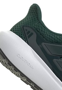 Zapatilla deportiva de malla verde con una plantilla blanca texturizada, que presenta una etiqueta "CLOUDFOAM" incrustada y acentos en gris oscuro en los laterales.