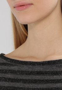 Pull noir et gris à rayures avec une bande texturée et scintillante au niveau de l'encolure, présentant un design à large encolure bateau.