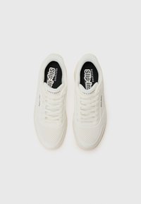 Baskets blanches Skechers avec une tige perforée, des lacets plats et un logo noir sur la languette. Bout arrondi et semelle rembourrée.