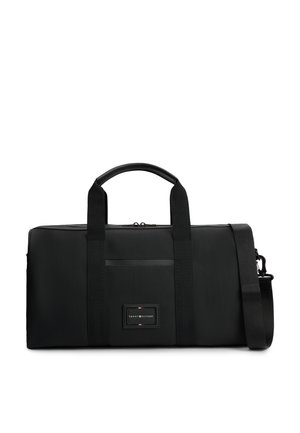 Schwarze rechteckige Reisetasche mit zwei Griffen, abnehmbarem Schulterriemen und vorderem Aufnäher-Logo mit kleinen roten, weißen und blauen Details.