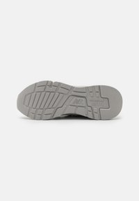 Sivi gumeni potplat New Balance 997R tenisica prikazuje teksturirani uzorak i utisnuti branding na bijeloj pozadini.