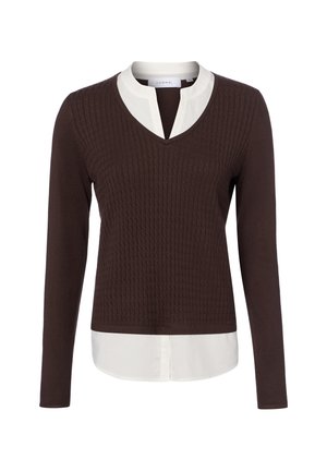 Pull en maille marron à manches longues avec motif texturé, superposé à une chemise blanche à col avec une ouverture en V.