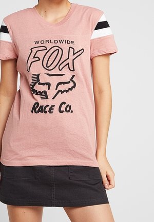 Ljust rosa kortärmad t-shirt med svart grafik av texten "FOX" och logotyp. Har svarta och vita randiga detaljer vid axlarna.