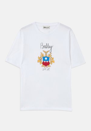 White cotton t-shirt featuring a colorful crest design with blue, red, and gold accents, and the text “Bally crest” in black script.