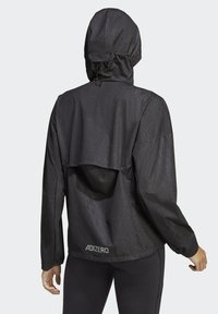 Giacca leggera nera con cappuccio, superficie texturizzata, polsini elastici e design morbido. Presenta il marchio "ADIZERO" sull'orlo.