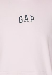 Felpa di cotone rosa chiaro, con il logo "GAP" ricamato in blu navy sul petto. Tessuto morbido, design a vestibilità rilassata.
