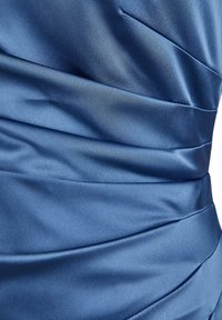 Gros plan sur un tissu en satin bleu avec des plis horizontaux créant une surface lisse, brillante et texturée.