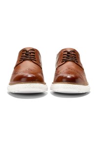 Scarpe eleganti in pelle marrone con finitura lucida, design wingtip e suola in gomma bianca. Presentano lacci marroni e leggere perforazioni.