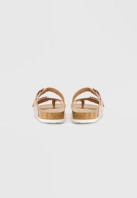 Καφέ σανδάλια με δύο ρυθμιζόμενες ιμάντες, φουσκωτή σόλα από φελλό και λευκή καουτσούκ σόλα. Ορατή υφή επιφάνειας και ασημένια αγκράφα.