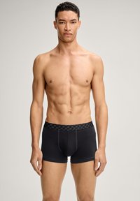 Mustat bokserialushousut, jotka on valmistettu pehmeästä kankaasta ja joissa on kuvioitu joustava vyötärönauha. Ominaisuuksia ovat tiukka istuvuus ja suora leikkaus jaloissa.