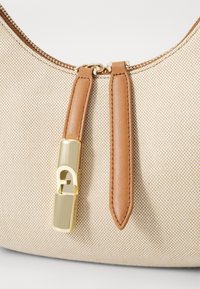 Beige textured canvas handbag with brown leather accents and a gold zipper pull featuring a unique lock closure.