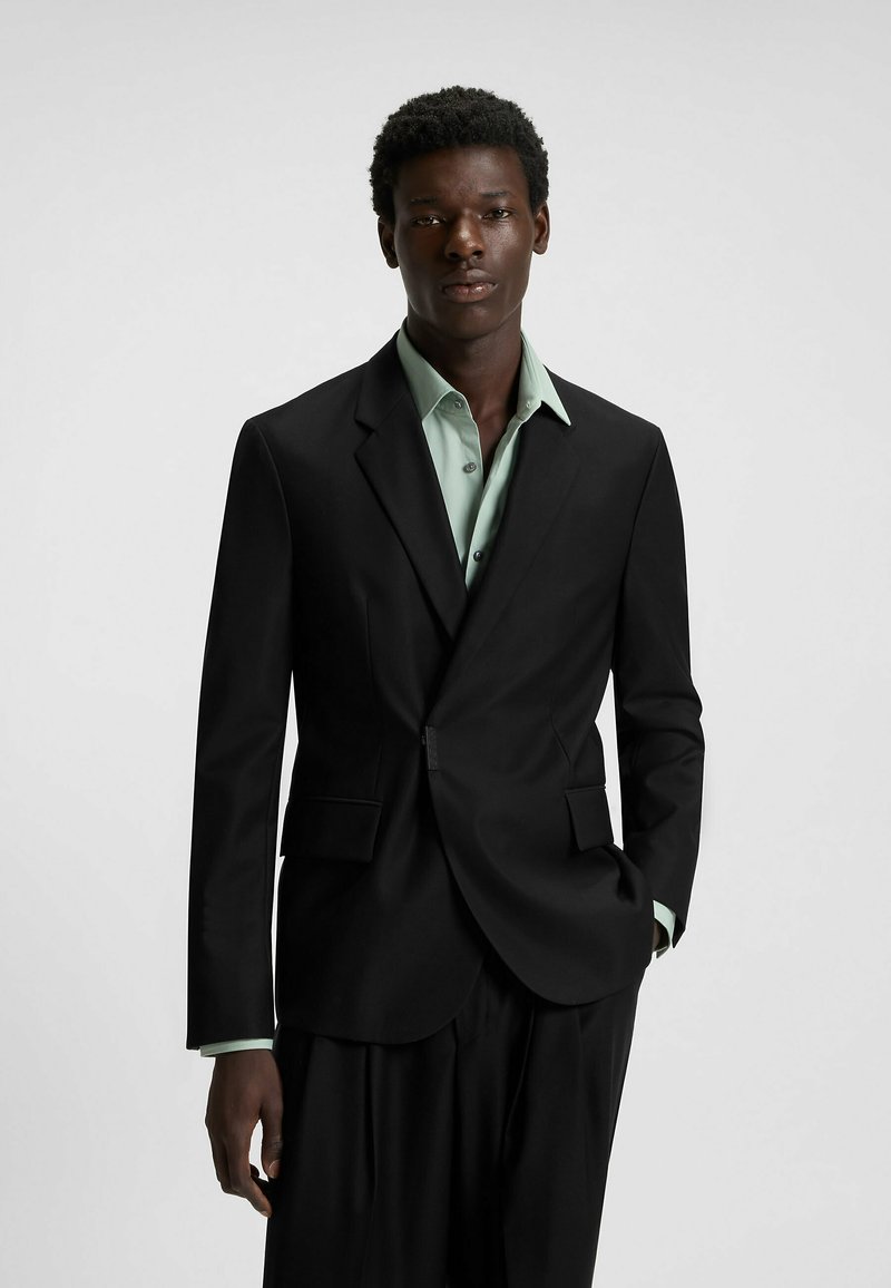 Black tailored blazer with notch lapels, paired with a mint green shirt. The fabric has a smooth texture and structured fit.