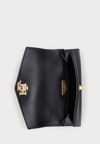 Μαύρη δερμάτινη τσάντα χειρός με κούμπωμα χρυσού λογότυπου. Ο εσωτερικός χώρος είναι λείος, με κομψό σχέδιο και ορθογώνιο σχήμα.