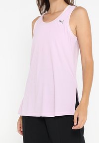 Ljusrosa ribbad linne med rund halsringning, sidslitsar och en liten svart Puma-logotyp på övre vänstra bröstet. Tillverkat av andningsbart material.