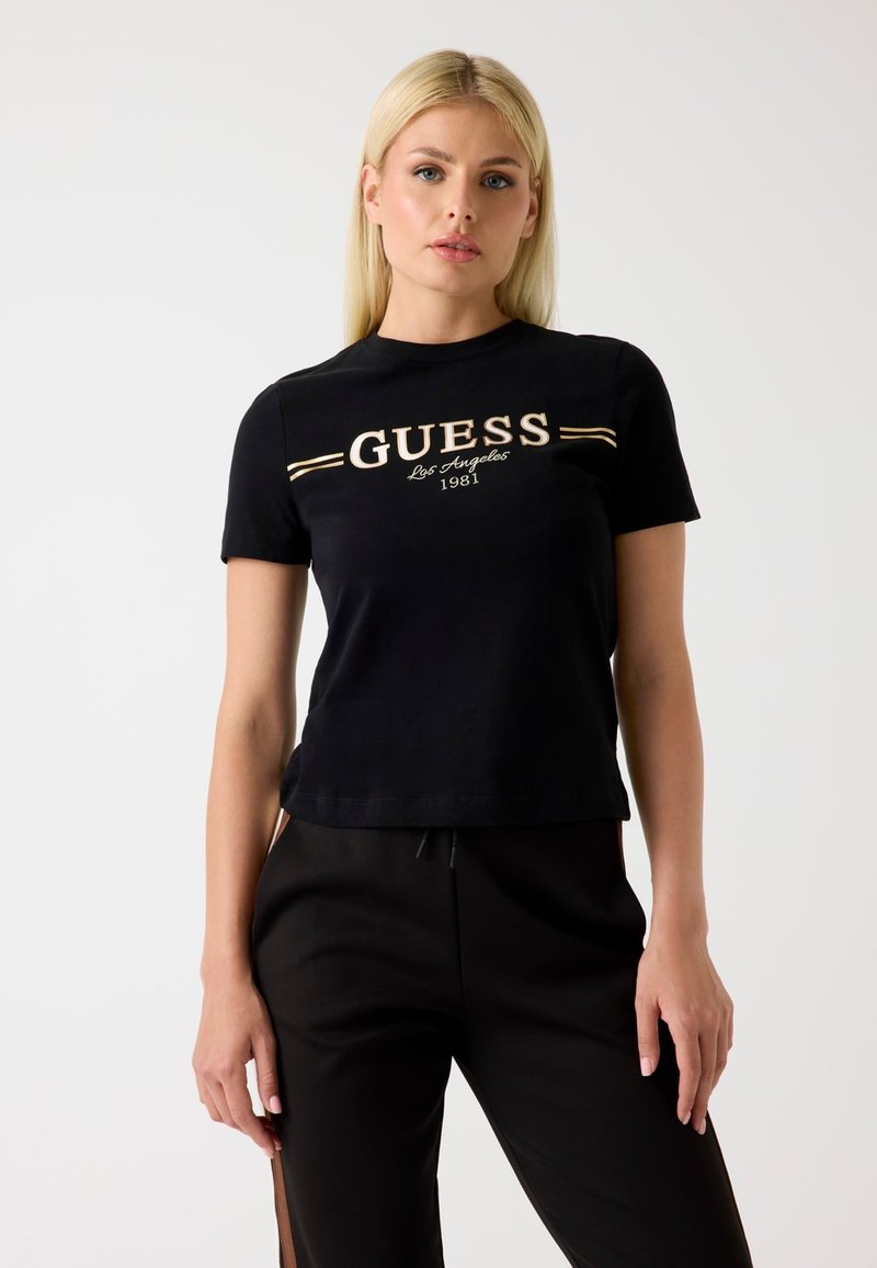 Čierne tričko s krátkymi rukávmi, s pozlátkovým logom "GUESS Los Angeles 1981" umiestneným v strede. Jednoduchý, pohodlný dizajn s okrúhlym výstrihom.