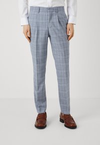 Pantaloni cu carouri bleu deschis, din țesătură împletită, cu față plată și pliuri laterale, asortați cu pantofi loafers maronii.