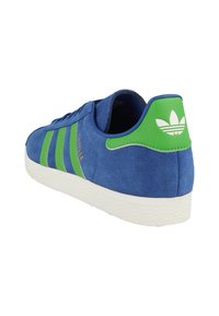 Sneaker blu in suede con accenti verdi e suola bianca, che presenta tre strisce e un logo Adidas sul tallone.